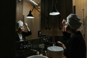 femme appliquant une crème de nuit devant son miroir salle de bain