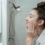 femme appliquant un soin régénérant sur son visage devant miroir naturel
