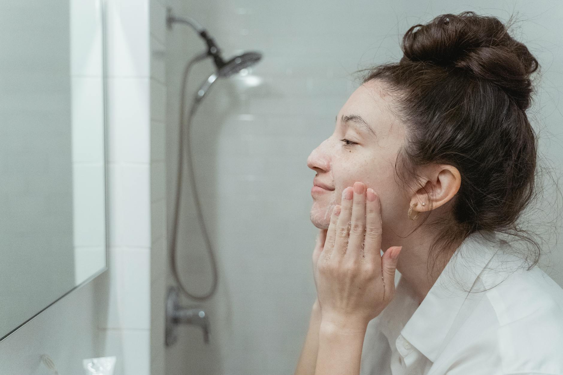 femme appliquant un soin régénérant sur son visage devant miroir naturel