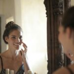 femme appliquant une crème visage devant miroir lumière naturelle