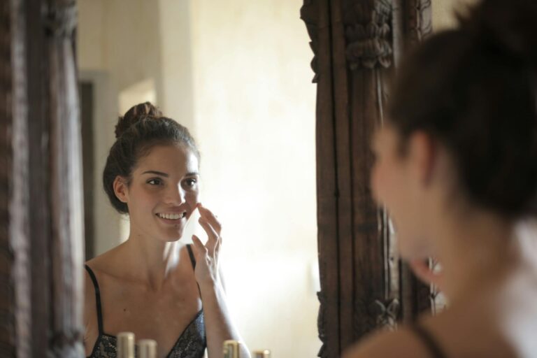 femme appliquant une crème visage devant miroir lumière naturelle