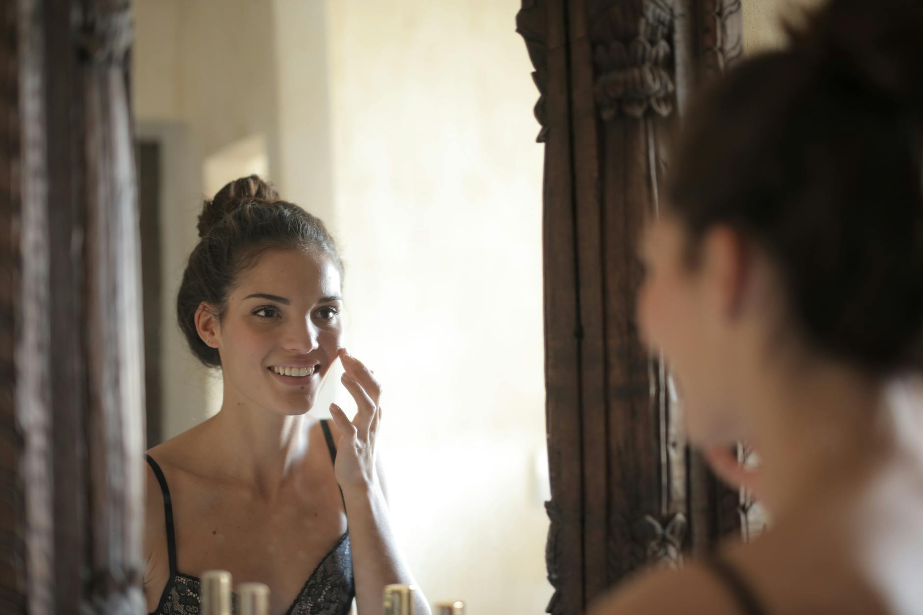 femme appliquant une crème visage devant miroir lumière naturelle