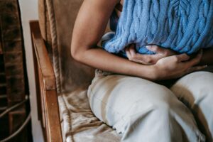 femme allongée sur canapé tenant bouillotte sur bas-ventre douloureux