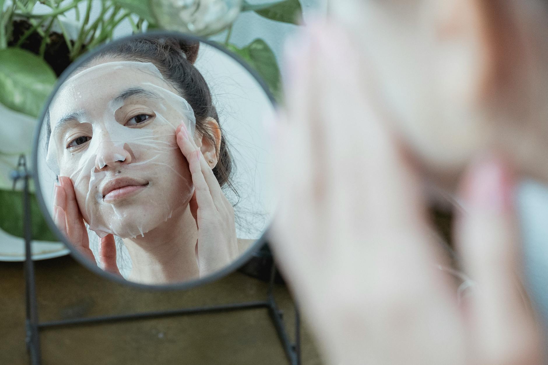 femme appliquant un masque tissu blanc sur son visage soins beauté
