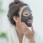 Plusieurs masques visage colorés disposés sur une tablette en bois clair, ambiance soin beauté naturel