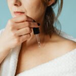 Femme appliquant un soin visage devant un miroir éclairé, routine beauté