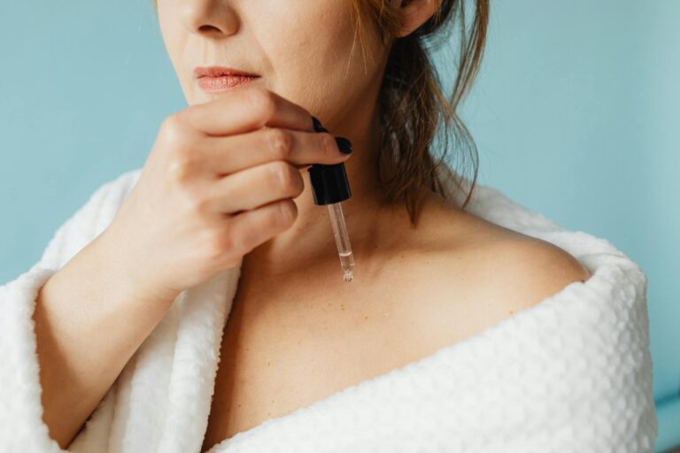 Femme appliquant un soin visage devant un miroir éclairé, routine beauté