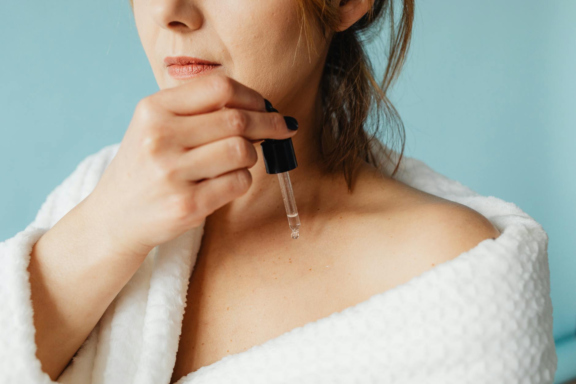 Femme appliquant un soin visage devant un miroir éclairé, routine beauté