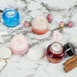 Routine skin care minimaliste posée sur marbre blanc, flacons soins visage