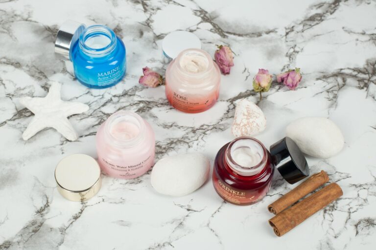 Routine skin care minimaliste posée sur marbre blanc, flacons soins visage