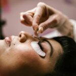 Esthéticienne appliquant une extension de cils sur une cliente allongée en institut