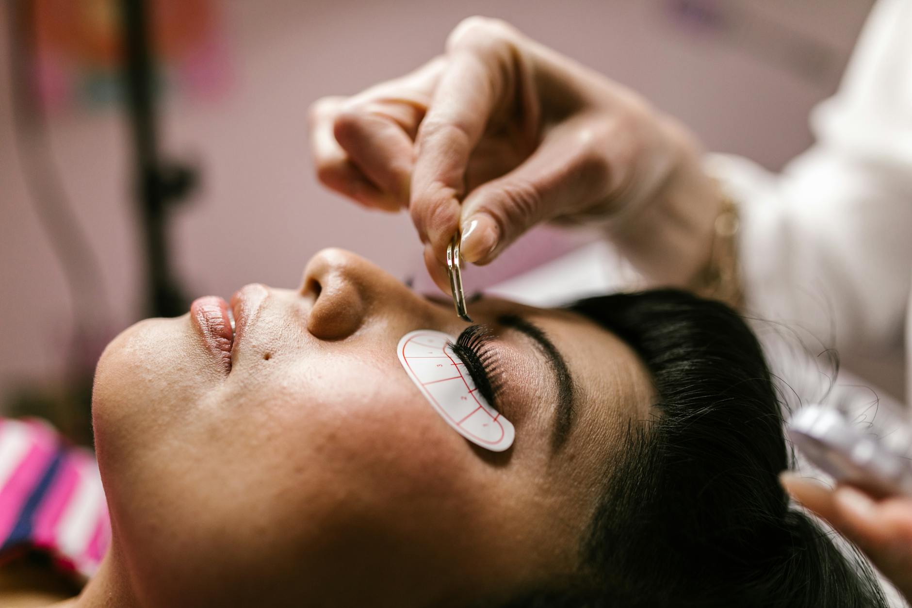 Esthéticienne appliquant une extension de cils sur une cliente allongée en institut