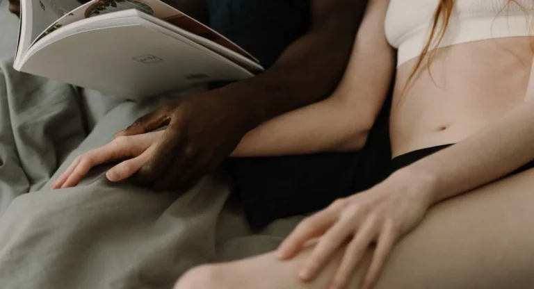 Deux mains enlacées sur des draps froissés après l'orgasme, ambiance douce