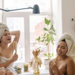 Femme sous la douche utilisant un gant exfoliant sur le bras