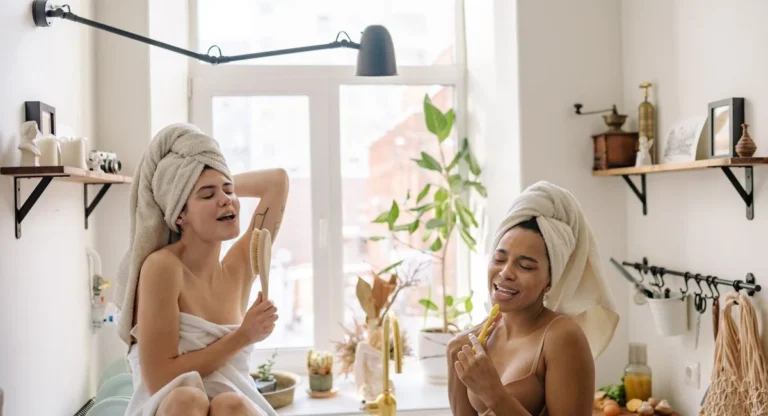 Femme sous la douche utilisant un gant exfoliant sur le bras