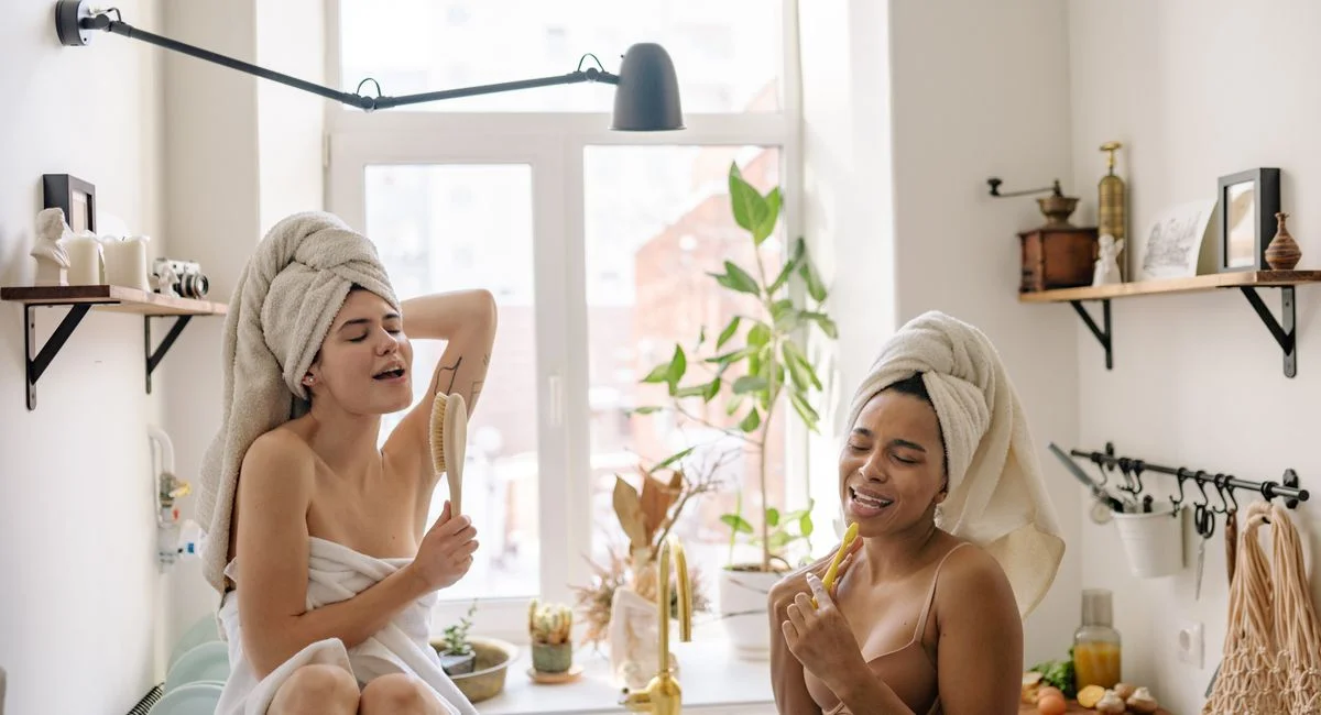 Femme sous la douche utilisant un gant exfoliant sur le bras