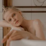 Femme aux cheveux bleus regardant son reflet dans le miroir