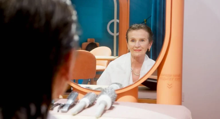 Femme devant miroir examinant quelques cheveux blancs repigmentés