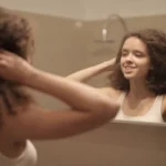 Femme essorant ses cheveux colorés devant miroir de salle de bain