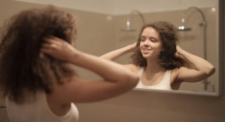 Femme essorant ses cheveux colorés devant miroir de salle de bain
