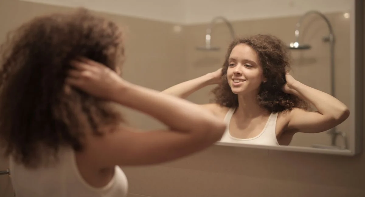 Femme essorant ses cheveux colorés devant miroir de salle de bain