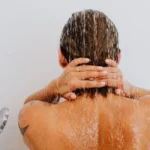 Femme sous la douche observant les cheveux tombés dans ses mains