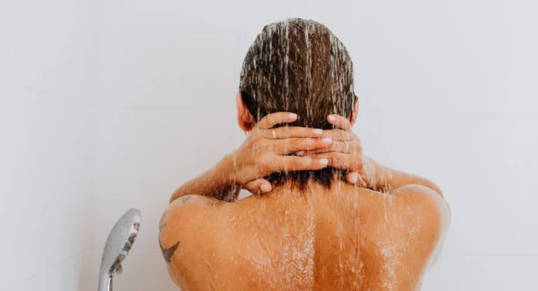 Femme sous la douche observant les cheveux tombés dans ses mains